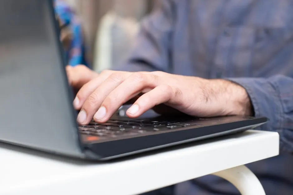 Close-up of hands typing on a laptop keyboard